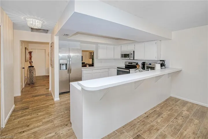 Kitchen featuring a peninsula, a kitchen breakfast bar, light countertops, and stainless steel appliances