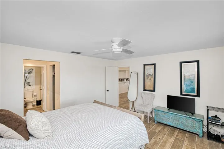Bedroom featuring wood finish floors, ensuite bathroom, and a ceiling fan