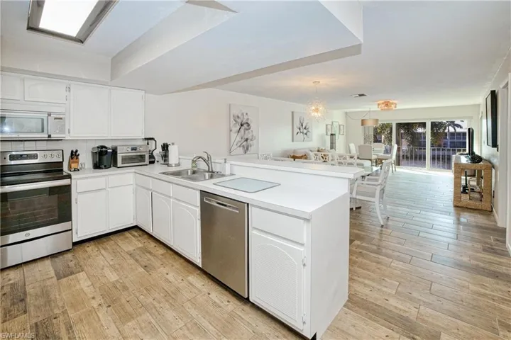Kitchen featuring appliances with stainless steel finishes, open floor plan, a peninsula, white cabinets, and light countertops