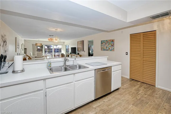 Kitchen with white cabinets, light countertops, stainless steel dishwasher, open floor plan, and a chandelier