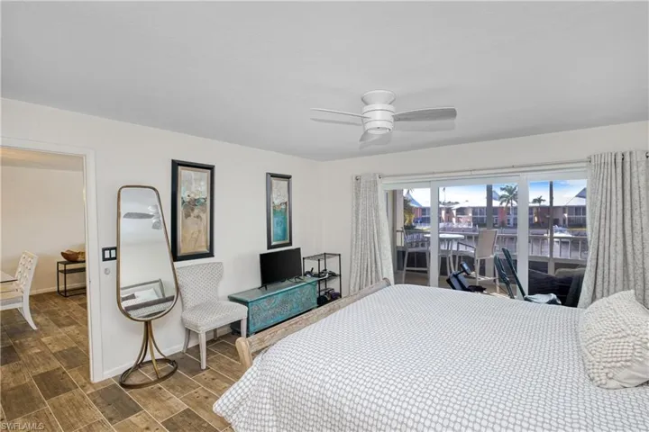 Bedroom with wood tiled floors, access to outside, and ceiling fan