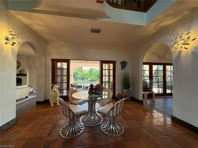 Dining area with arched walkways, french doors, and dark tile patterned flooring
