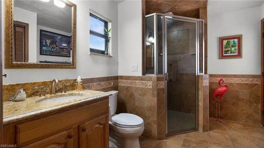 Full bath with tile walls, vanity, a wainscoted wall, and a shower stall
