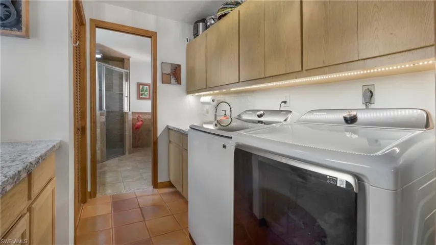 Washroom featuring light tile patterned flooring, separate washer and dryer, and cabinet space