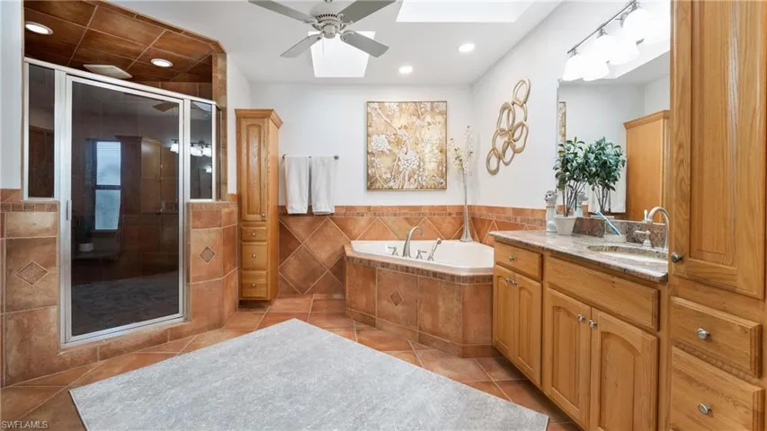 Bathroom with a bath, a shower stall, vanity, light tile patterned floors, and tile walls