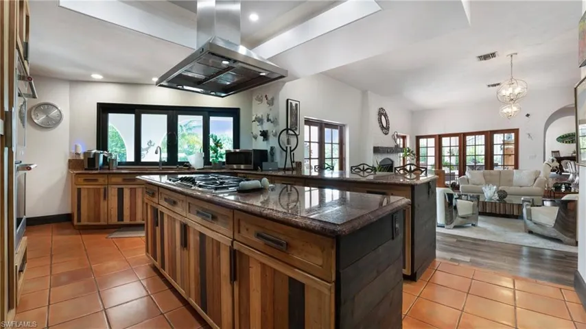 Kitchen featuring island exhaust hood, a center island, dark stone countertops, french doors, and open floor plan