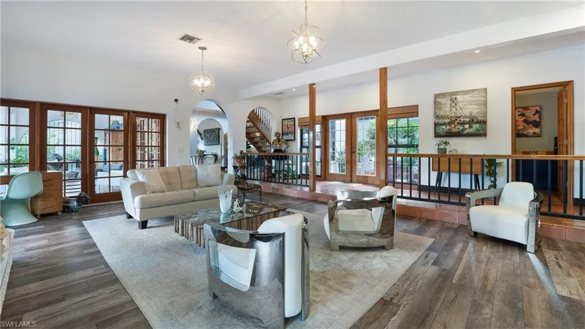 Living area with arched walkways, french doors, dark wood-style floors, a chandelier, and recessed lighting