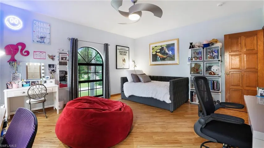 Bedroom featuring an office area, wood finished floors, and a ceiling fan