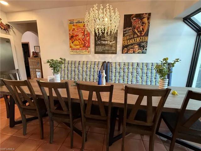 Dining area with arched walkways, a chandelier, and light tile patterned floors