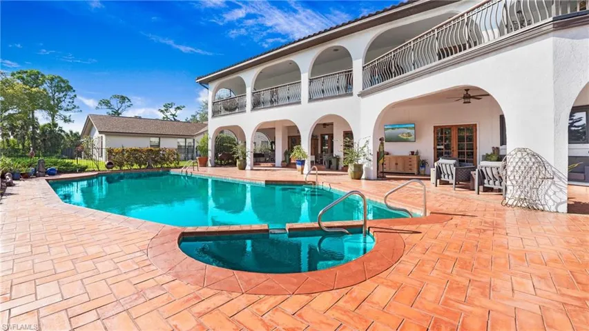 View of pool with ceiling fan, a patio, a pool with connected hot tub, and a balcony