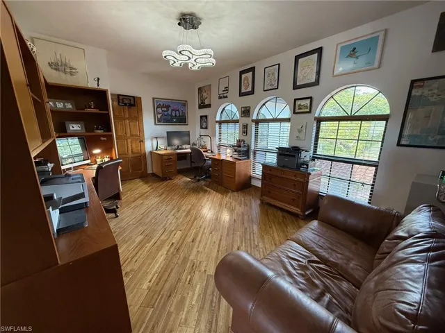 Home office with light wood finished floors and a chandelier