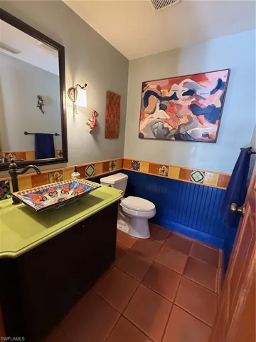 Bathroom featuring dark tile patterned flooring, vanity, and a wainscoted wall