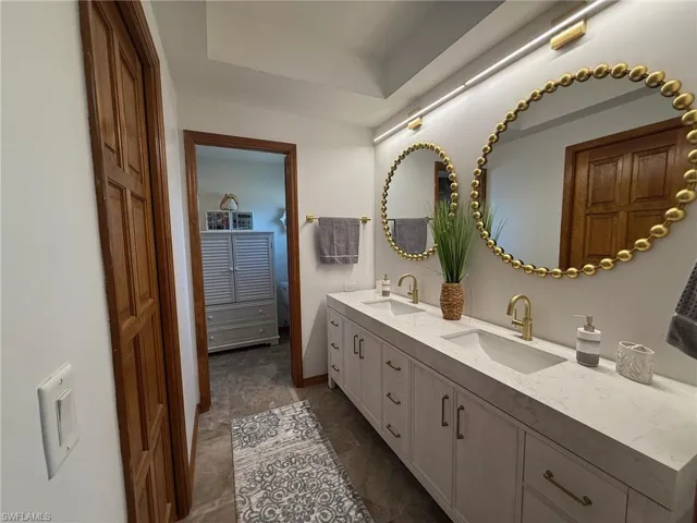 Full bathroom with double vanity and baseboards