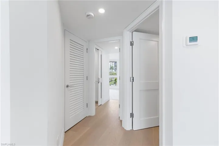 Hallway with light wood finished floors and recessed lighting