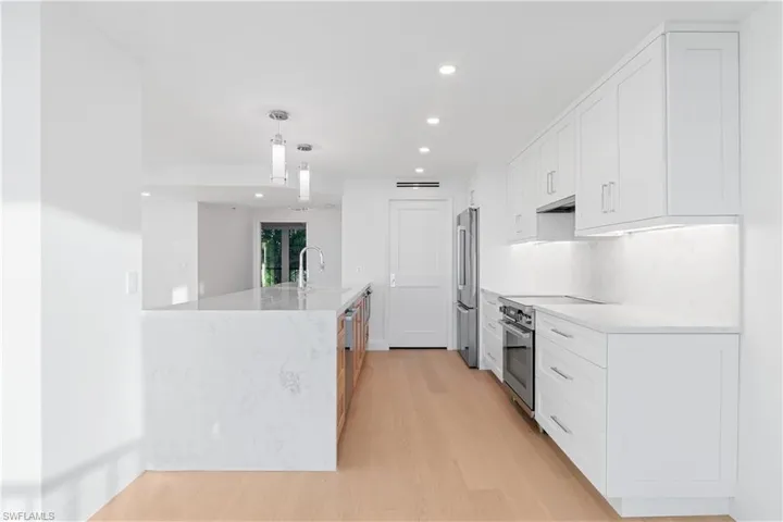 Kitchen featuring white cabinets, recessed lighting, light stone countertops, decorative light fixtures, and stainless steel appliances