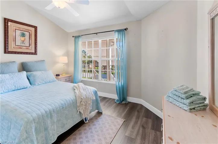 Bedroom with ceiling fan, vaulted ceiling, and wood-type flooring