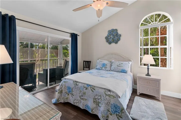 Bedroom featuring dark wood-type flooring, ceiling fan, vaulted ceiling, and access to outside
