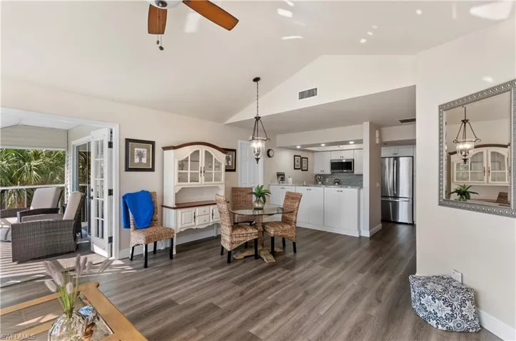 Dining space with ceiling fan with notable chandelier, dark hardwood / wood-style floors, and high vaulted ceiling