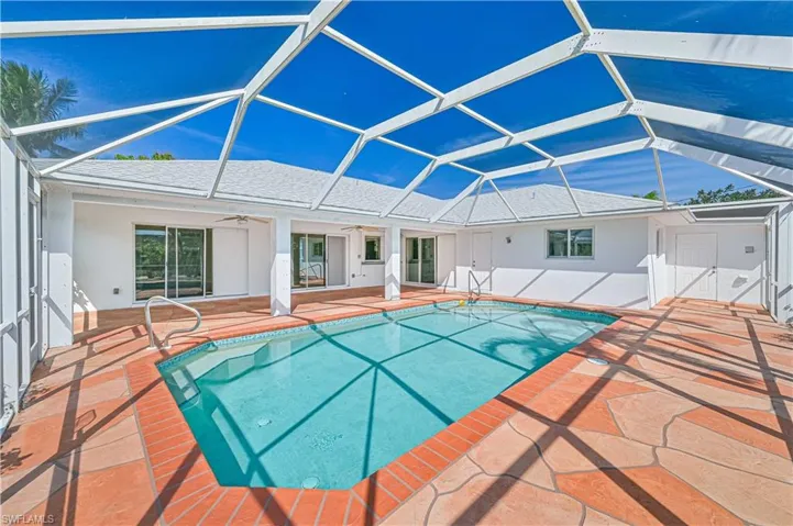 Outdoor pool featuring ceiling fan, glass enclosure, and a patio