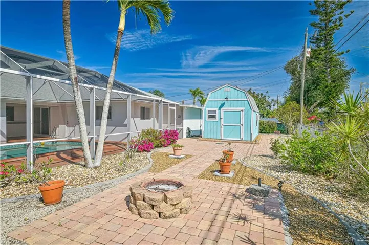 View of yard with an outbuilding, a storage shed, a patio area, glass enclosure, and a fire pit