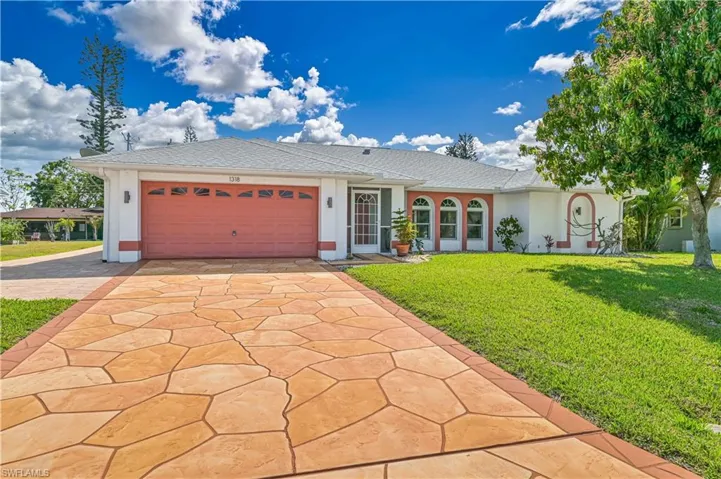 Single story home featuring concrete driveway, stucco siding, an attached garage, and a front yard