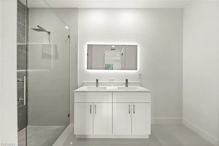 Full bathroom with double vanity, a shower stall, and a textured wall