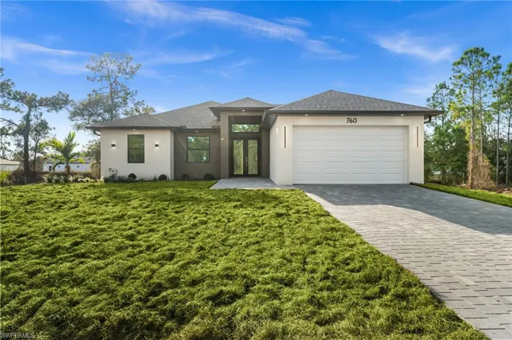 Prairie-style house with french doors, decorative driveway, a garage, and stucco siding
