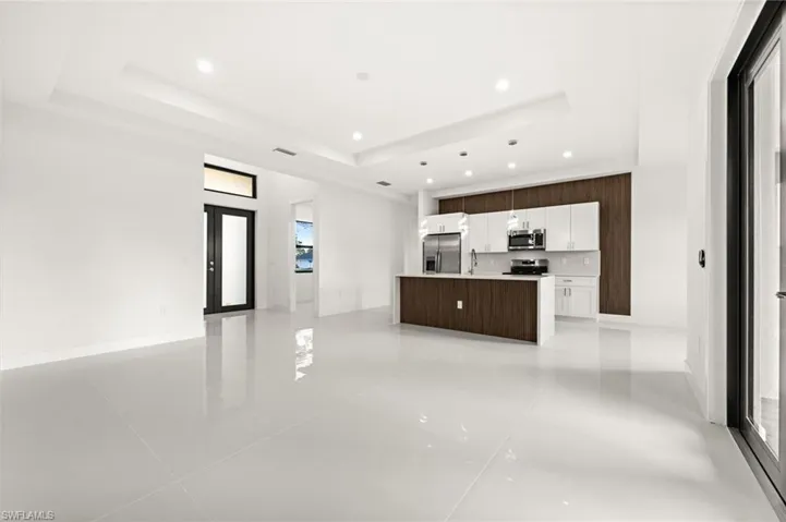 Unfurnished living room featuring a raised ceiling, recessed lighting, and light tile patterned flooring