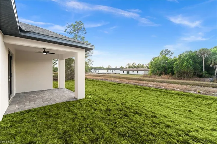 View of green lawn with ceiling fan and a patio area