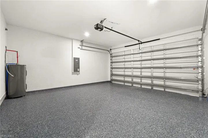 Garage featuring electric panel, water heater, and a garage door opener