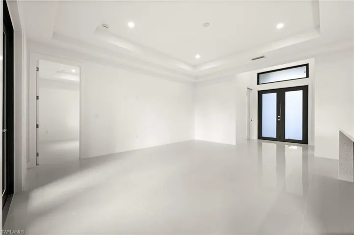 Unfurnished room featuring french doors, recessed lighting, light tile patterned flooring, and a raised ceiling