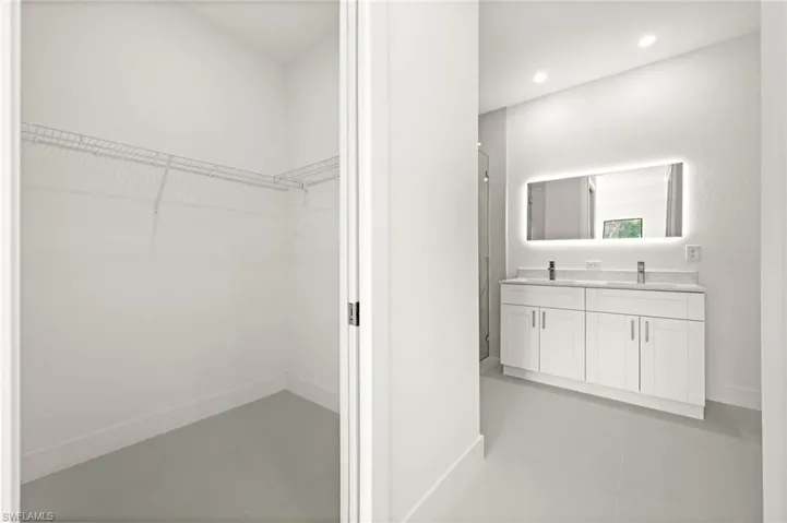 Bathroom featuring double vanity, a walk in closet, tile patterned floors, a stall shower, and recessed lighting
