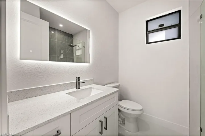Full bathroom featuring vanity, a textured wall, and tiled shower