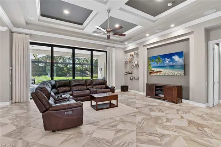 Living area featuring large format tile flooring, a tray ceiling with recessed lighting and a ceiling fan, and expansive sliding glass doors