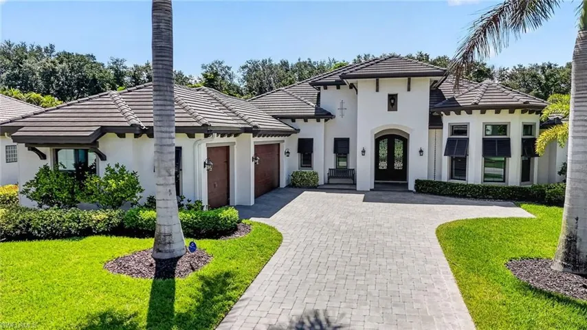 Stucco exterior residence featuring a tiled roof and a paver driveway