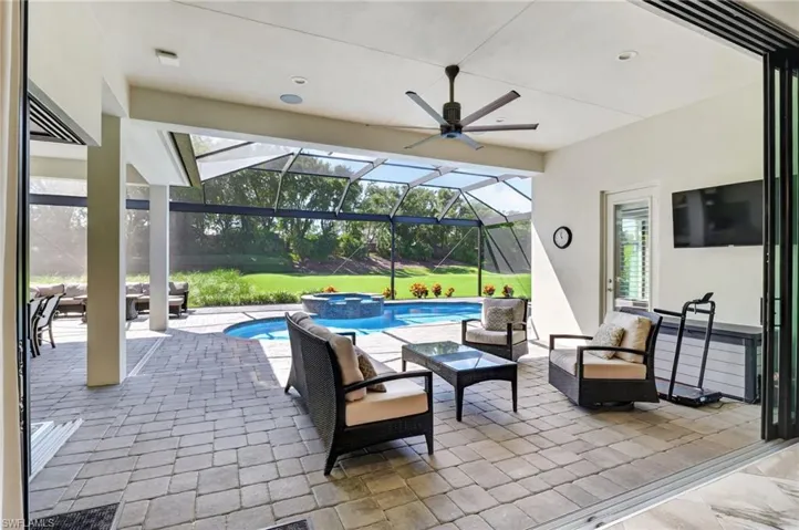 Expansive paver patio with a screened enclosure, featuring a built-in pool and spa