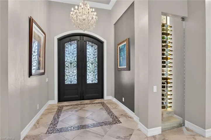 Arched double entry doors with decorative ironwork and obscured glass panels, complemented by a crystal chandelier