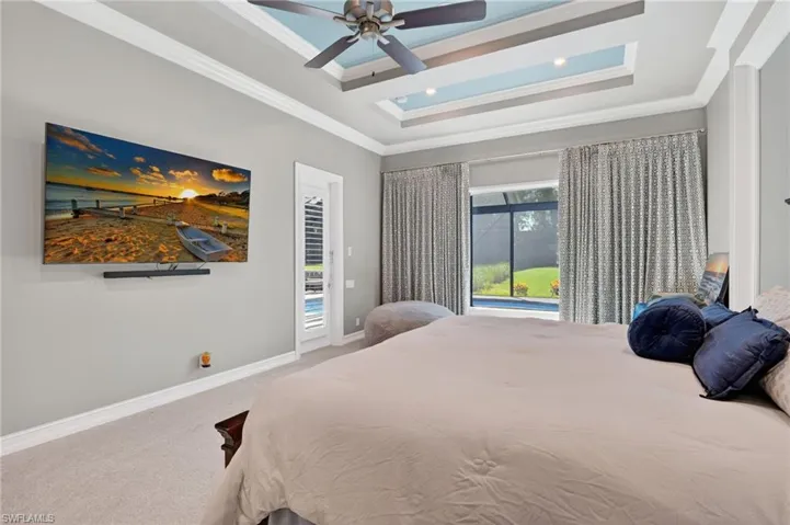 Room featuring a tray ceiling with recessed lighting, crown molding, and a ceiling fan