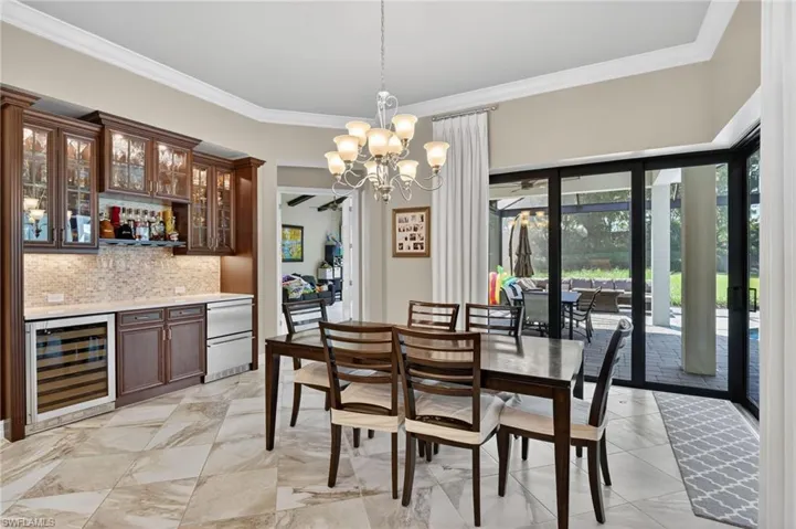 Dining area featuring a built-in wet bar with glass-front cabinetry, a wine cooler, and under-cabinet lighting