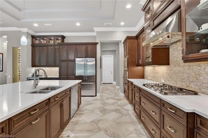 Gourmet kitchen featuring dark wood cabinetry, white countertops, stainless steel appliances, a gas cooktop, and a tile backsplash