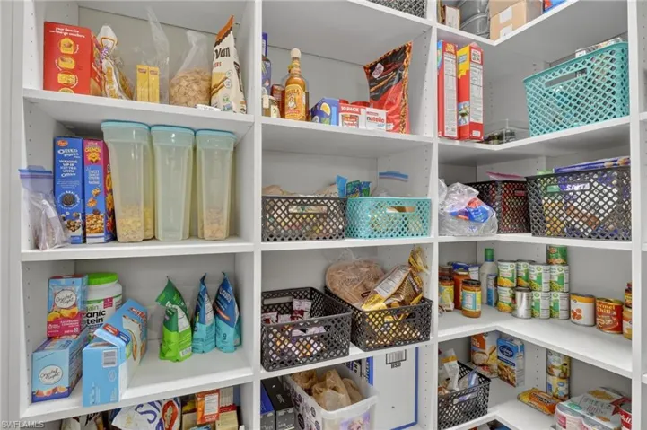Custom pantry featuring white shelving, adjustable shelf heights, and corner storage maximizing utility