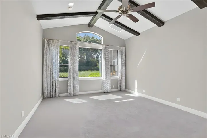 Den with vaulted ceiling with exposed wood-finish beams and a ceiling fan, complemented by recessed lighting