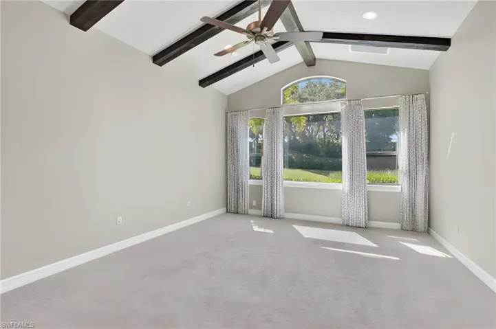 Den with vaulted ceiling featuring exposed wood beams and a ceiling fan
