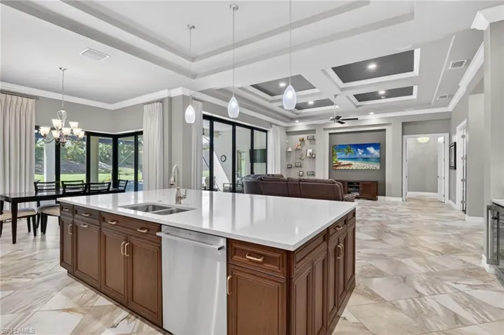 Spacious kitchen island featuring a dual basin sink, integrated dishwasher, and white countertop