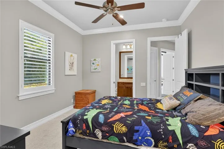 Bedroom featuring a ceiling fan with integrated lighting, crown molding, and plantation shutters