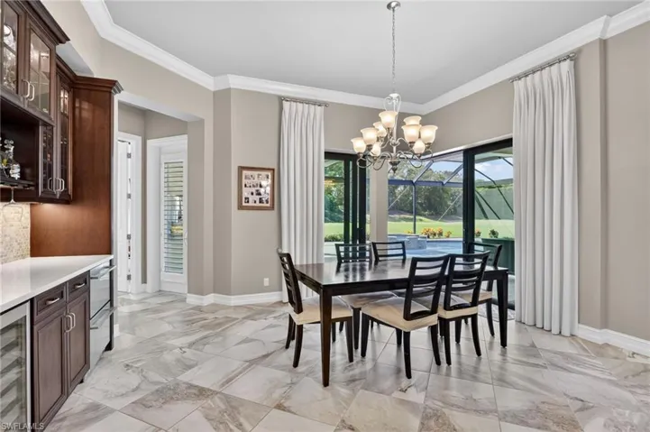 Dining area with large format tile flooring, crown molding, and a multi-arm chandelier