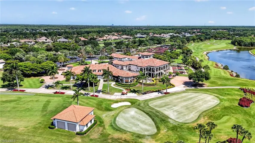 Expansive golf course property featuring a large Mediterranean-style structure with a tile roof, a manicured green, a water feature, and mature palm trees