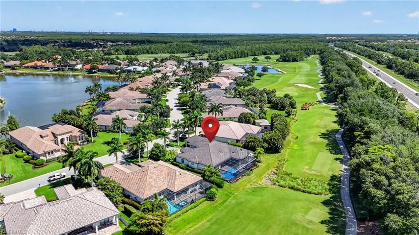 Aerial perspective showcasing a residential community with a large body of water, golf course, and highway infrastructure