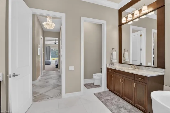 Spacious bathroom featuring a dual vanity with a light-toned countertop, a large framed mirror, and a built-in bathtub