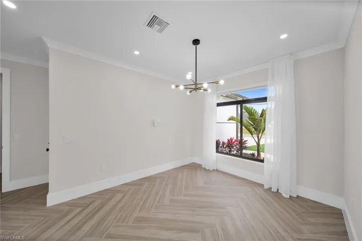 Empty room featuring baseboards, visible vents, and crown molding